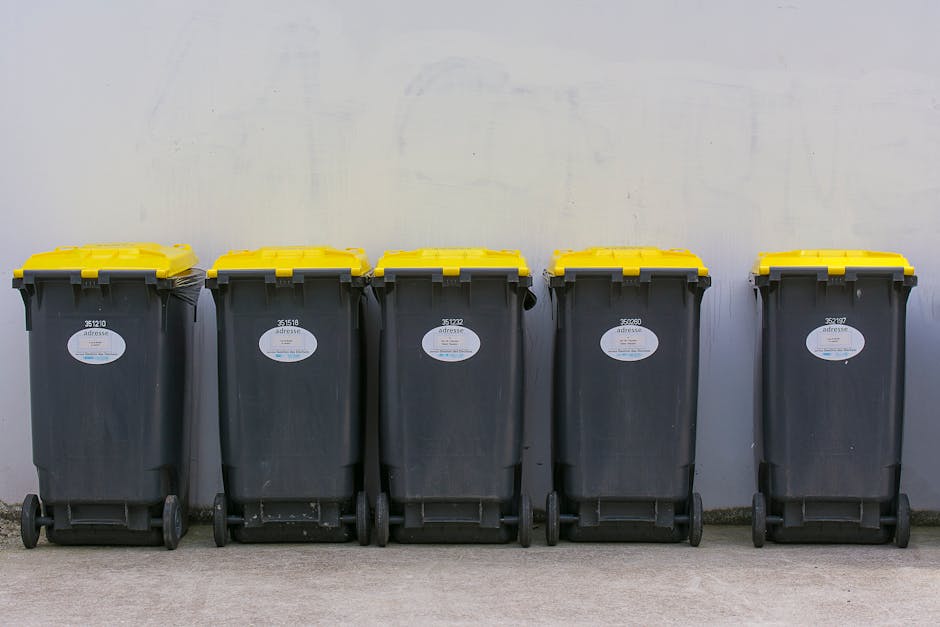 A close-up view of a large pile of mixed waste and rubbish, including black and white plastic garbage bags, used car tires, a yellow plastic container, and various discarded materials, all strewn acro